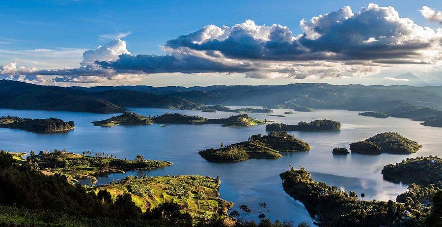 Dugout canoe gliding across the serene waters of Lake Bunyonyi with misty hills in the background